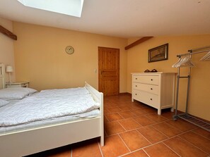 Quarto com cama, penteadeira, relógio, porta e janela.