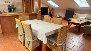 A dining area with a table and chairs, a kitchen area with a counter and appliances, a sofa, and a window. - Charming top floor apartment near the Baltic Sea Ideal for families of up to 6 people (Rövershagen)