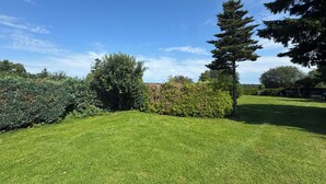 A well-maintained grassy lawn with a variety of shrubs and trees, providing a natural and serene outdoor setting. - Charming top floor apartment near the Baltic Sea Ideal for families of up to 6 people (Rövershagen)