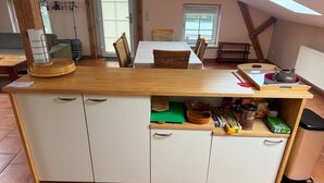 A kitchen with a wooden countertop, white cabinets, and a dining area with a table and chairs. - Charming top floor apartment near the Baltic Sea Ideal for families of up to 6 people (Rövershagen)