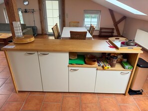 A kitchen with a wooden countertop, white cabinets, and a dining area with a table and chairs.