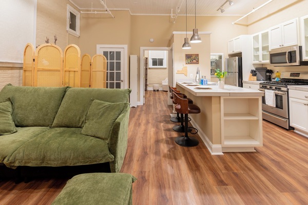 Spacious open layout with a cozy green sofa, stylish kitchen island, and inviting bar seating—perfect for cooking, relaxing, and enjoying time together.