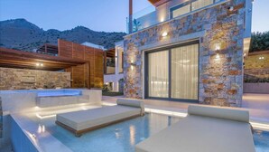 A modern outdoor pool area with lounge chairs and a stone wall.