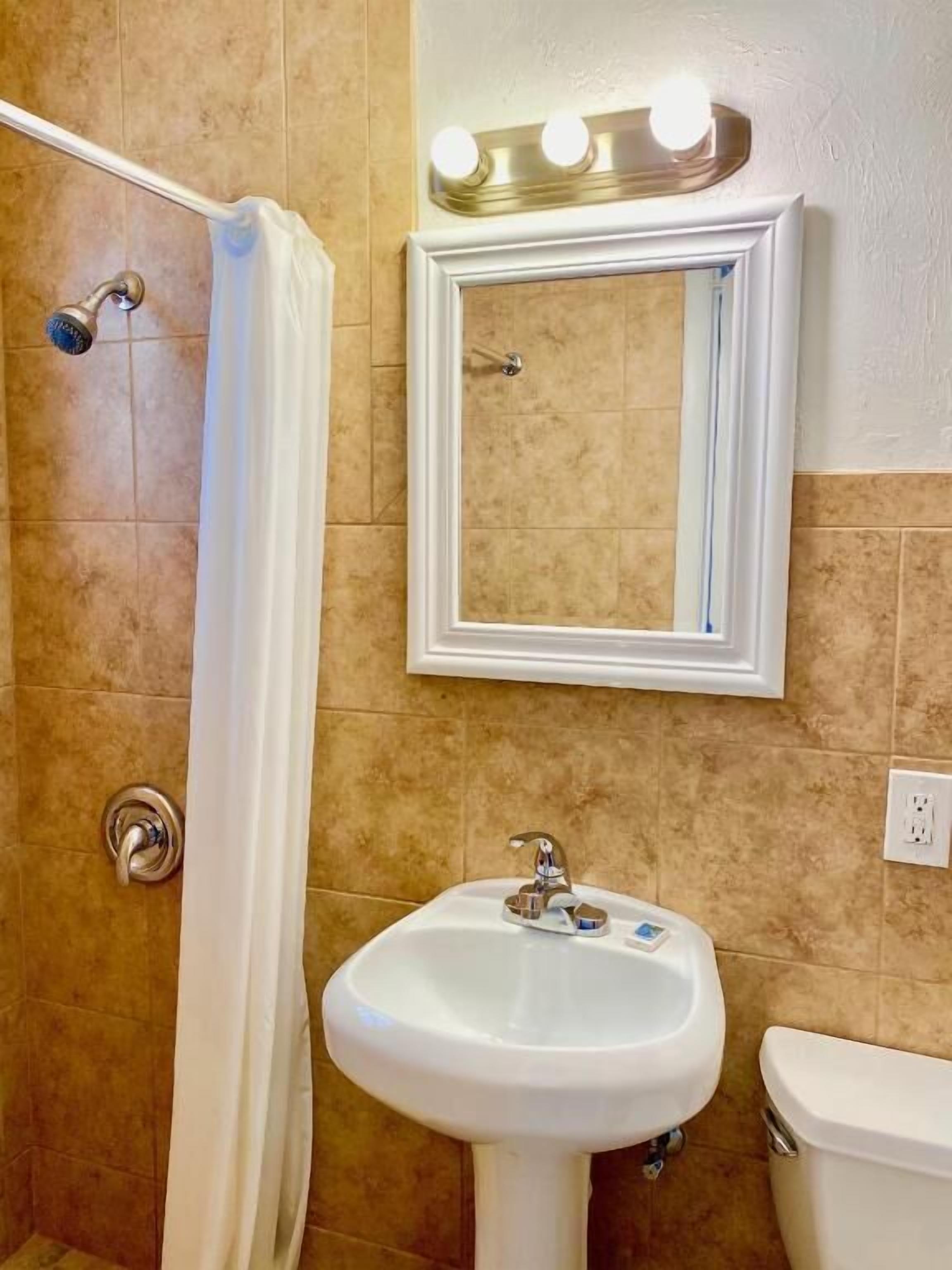 A bathroom with a shower, a sink, and a toilet.