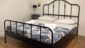 A bed with a metal frame, a bedside table with a lamp, and a small picture frame on the wall.