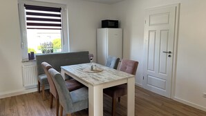 En spiseplads med et bord, stole, en bænk, en mikrobølgeovn og en dør.