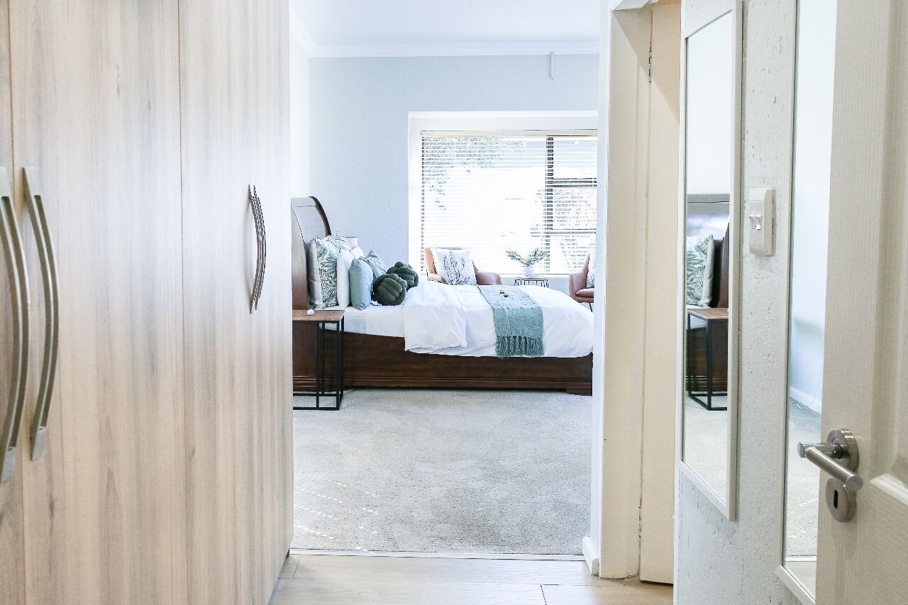 A bedroom with a bed, bedside tables, and a window with blinds.