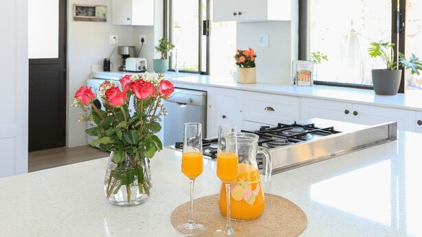 A modern kitchen with white cabinets, a gas stove, and a large window. - Kirrin House (Benoni)