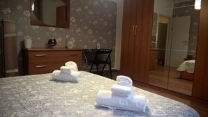 A hotel room with a bed, a wooden dresser, a chair, a mirror, and a wardrobe. - Stella apartment 10 min. from Venice (Venezia)