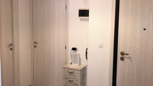 A hallway with wooden flooring, white doors, a small white cabinet, and a ceiling light fixture. - Stella apartment 10 min. from Venice (Venezia)