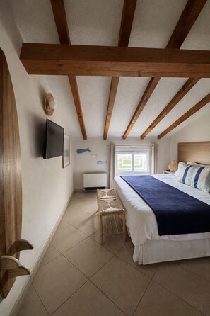 Ein Schlafzimmer mit Bett, Fernseher, Fenster und einem kleinen Tisch.