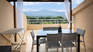 Um alpendre coberto com mesa e cadeiras, luminária pendente e vista para montanhas.