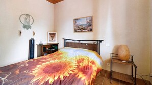 Une chambre à coucher avec un lit, une table de chevet, une lampe, un tableau au mur et une fenêtre.