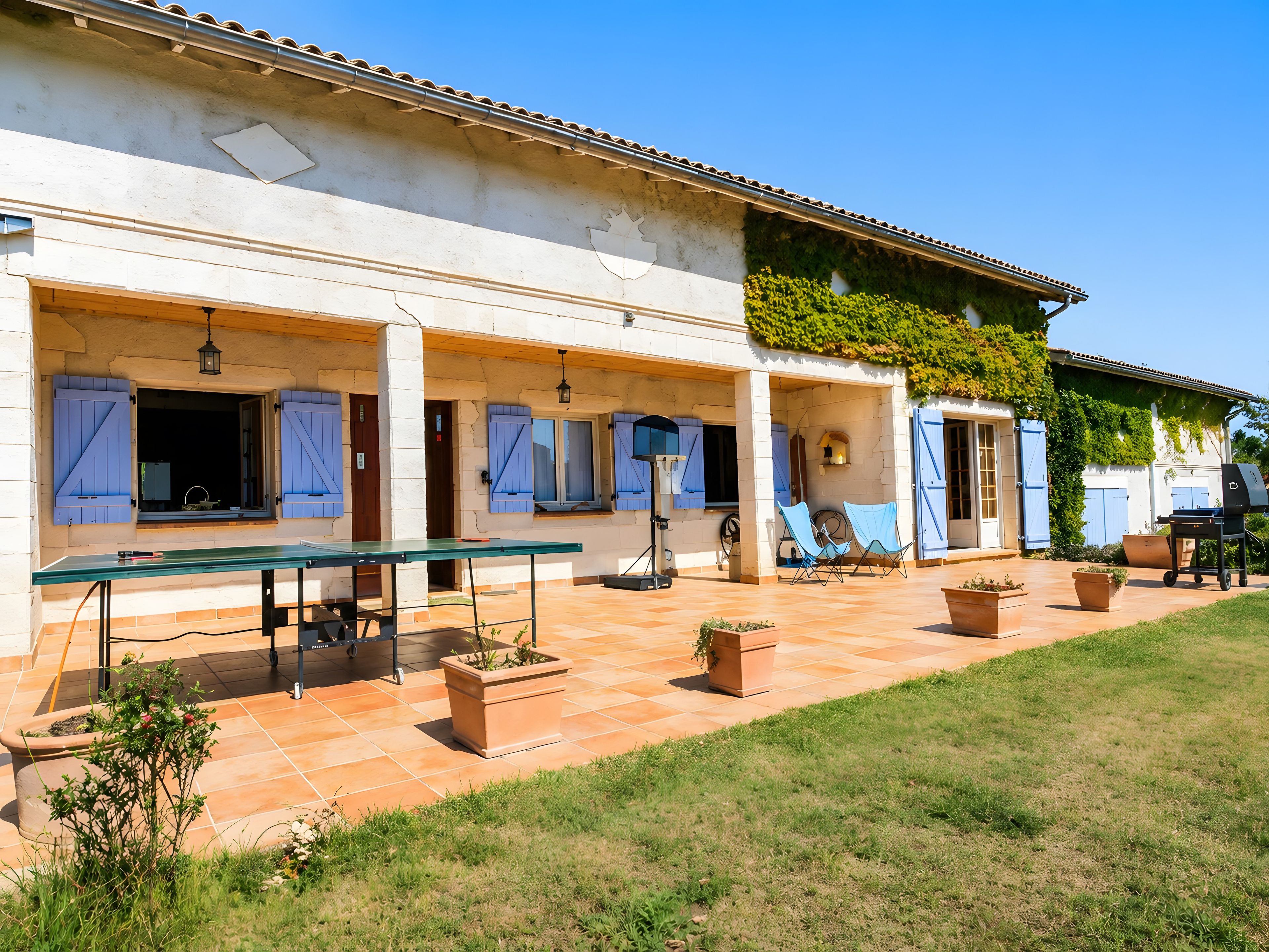 Une maison dotée d’un patio couvert, d’un espace salon extérieur et d’un coin barbecue.