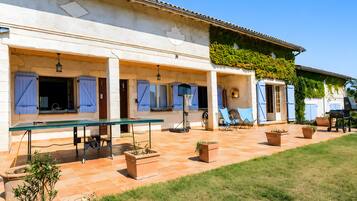 Une maison dotée d’un patio couvert, d’un espace salon extérieur et d’un coin barbecue.