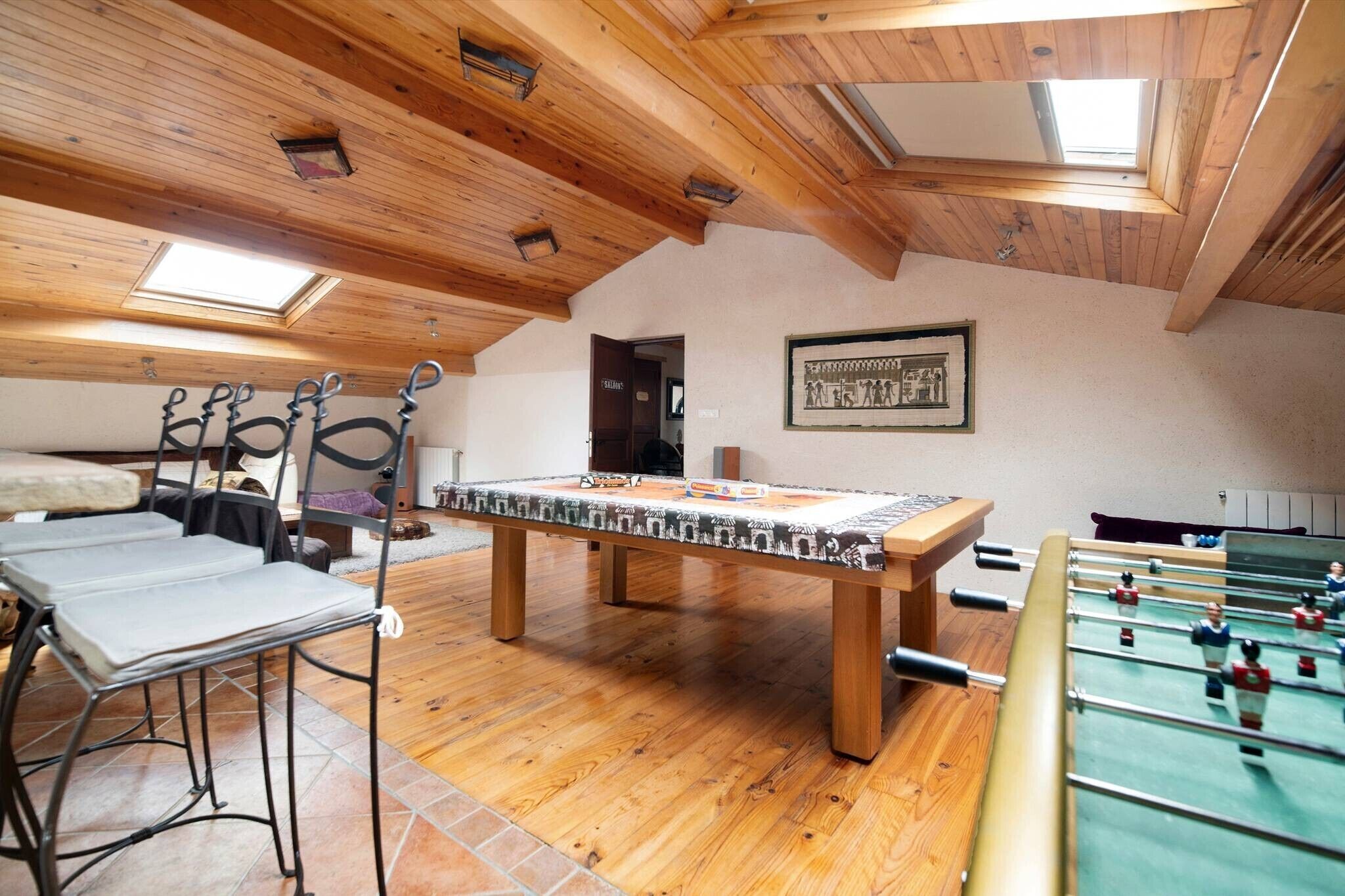A room with a foosball table, a pool table, and a billiards table.
