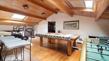 Una habitación con mesa de futbolín, mesa de billar y mesa de carambola.
