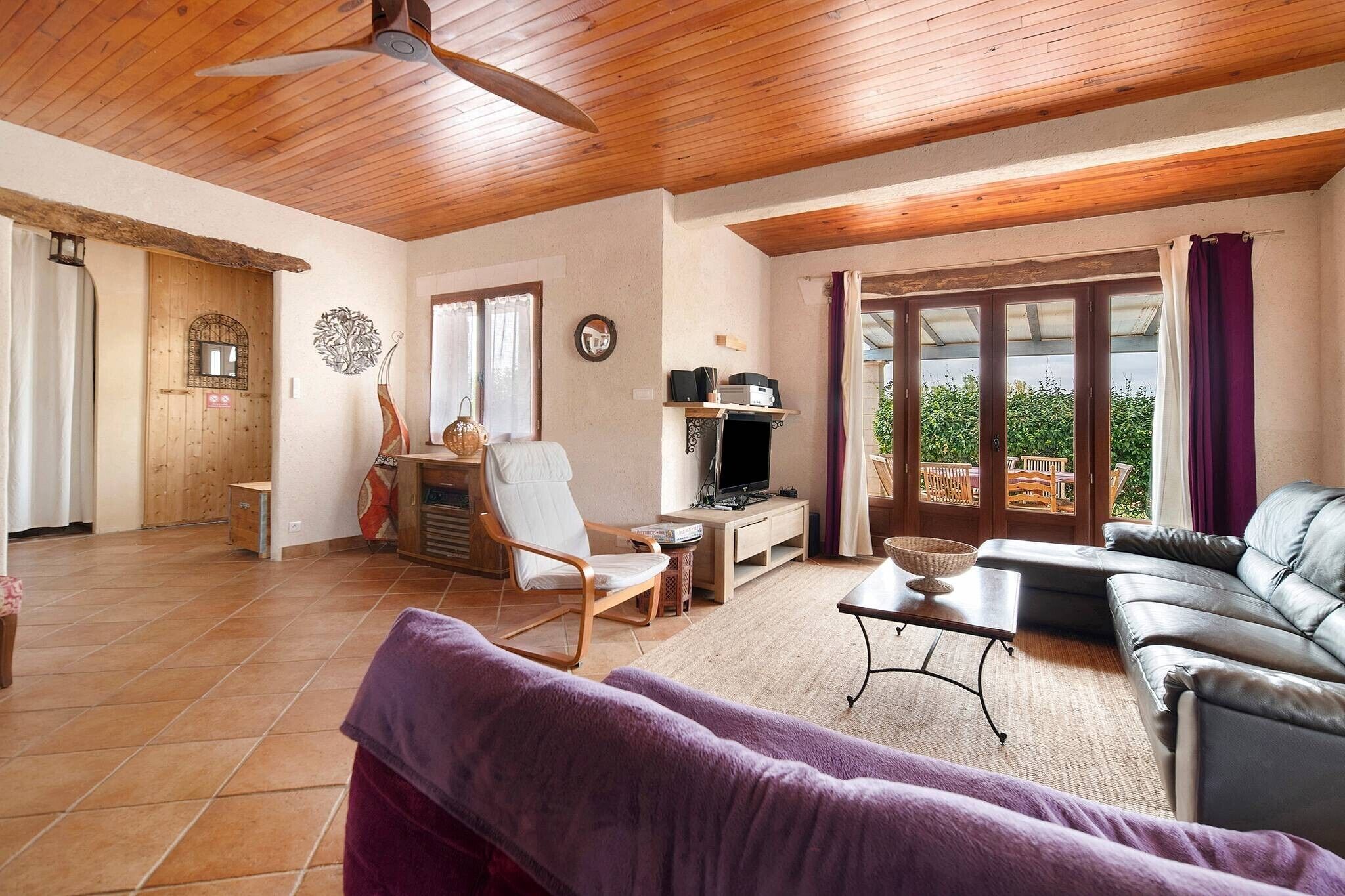 A spacious living area with a ceiling fan, a sofa, a TV, and a dining table.