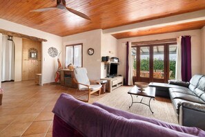 Un grand salon doté d’un ventilateur de plafond, d’un canapé, d’une télévision et d’une table à manger.