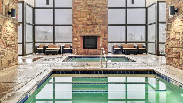 A pool area with stone walls, large windows, and seating.