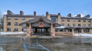 A hotel entrance with a covered lobby, a clear sky, and snow on the roof.