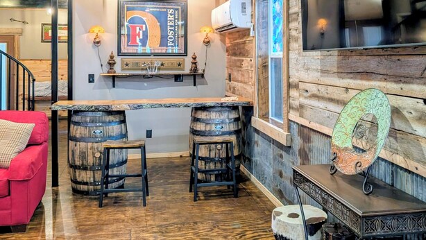 Un intérieur rustique avec des poutres en bois au plafond, un coin bar avec des tabourets et un canapé rouge.