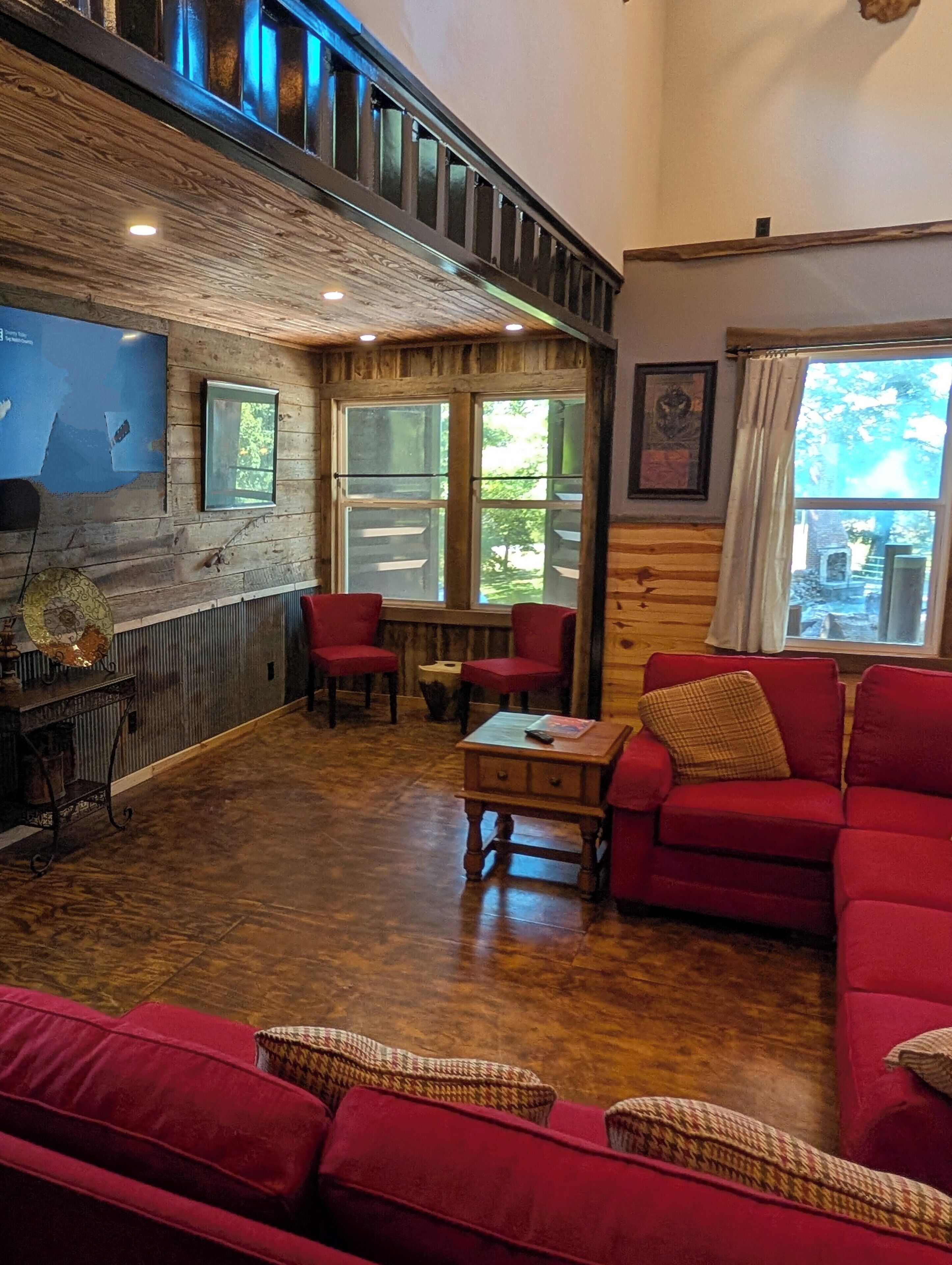 Une pièce chaleureuse avec un plafond en bois, des meubles rembourrés de couleur rouge et une grande fenêtre donnant sur l’extérieur.