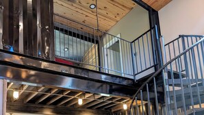 Un intérieur spacieux avec un plancher en bois, un escalier et une porte portant l’inscription « Tex ».