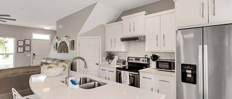 Una cocina moderna con armarios blancos, electrodomésticos de acero inoxidable y una isla curva con un lavamanos.