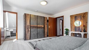 Un dormitorio con una cama grande, un armario de madera y un espejo con marco circular.