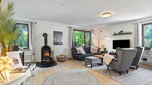 Una sala de estar moderna con chimenea, asientos cómodos y ventanas amplias.