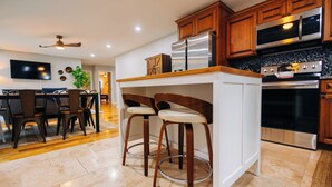 Una cocina moderna con armarios de madera, electrodomésticos de acero inoxidable y una barra con taburetes.
