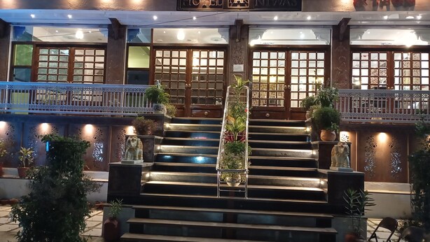 A hotel entrance with a staircase leading to the main doors, flanked by potted plants and decorative elements. - Har Niwas (Udaipur)