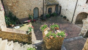 A courtyard with stone walls, potted plants, and a small table. - La Loggetta, a refuge in the heart of authentic Tuscany (colle di val d'elsa)