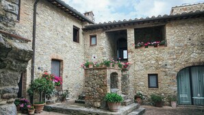 A stone courtyard with potted plants and a small fountain. - La Loggetta, a refuge in the heart of authentic Tuscany (colle di val d'elsa)
