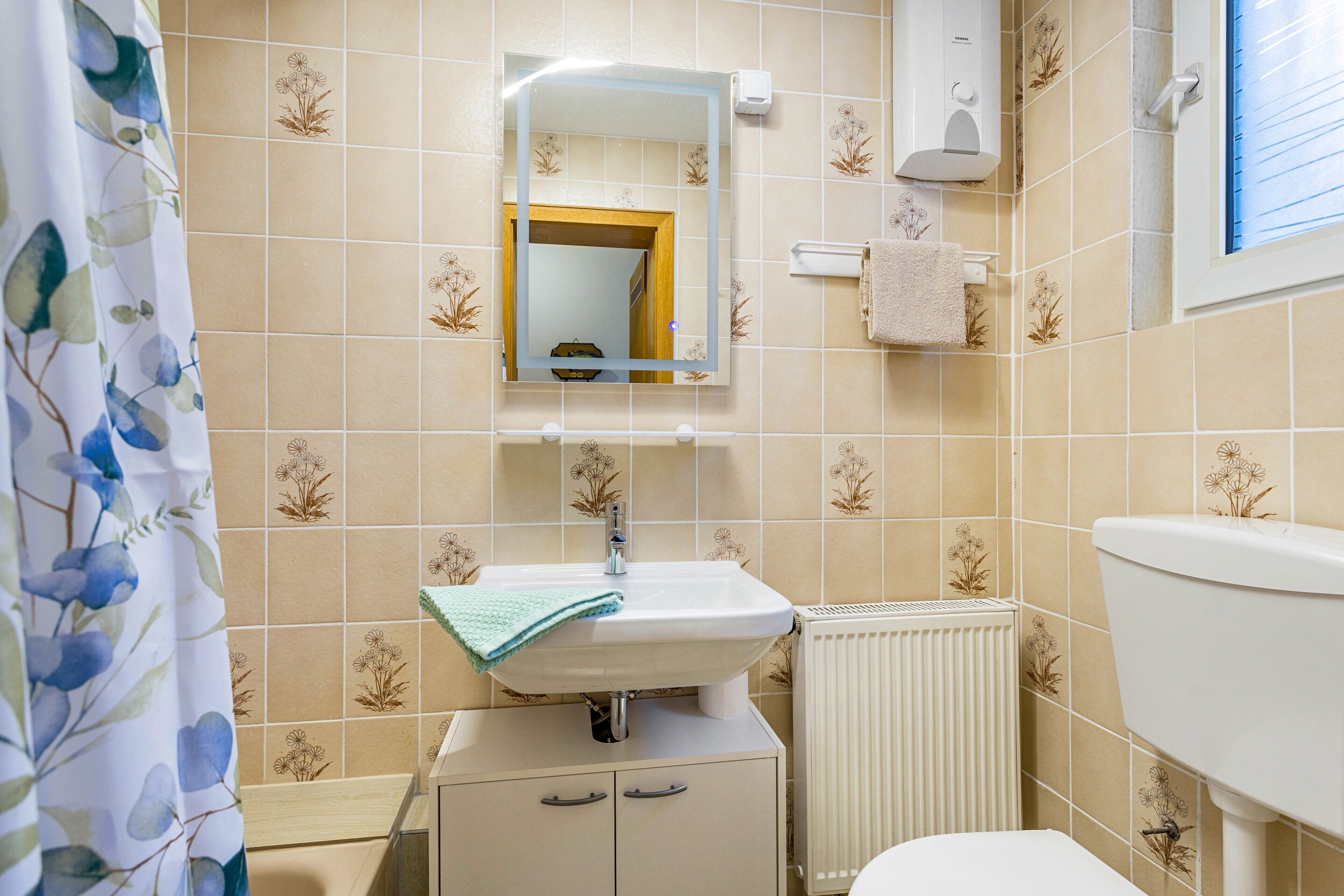 Ein Badezimmer mit Waschbecken, Spiegel, Handtuchhalter und Toilette.