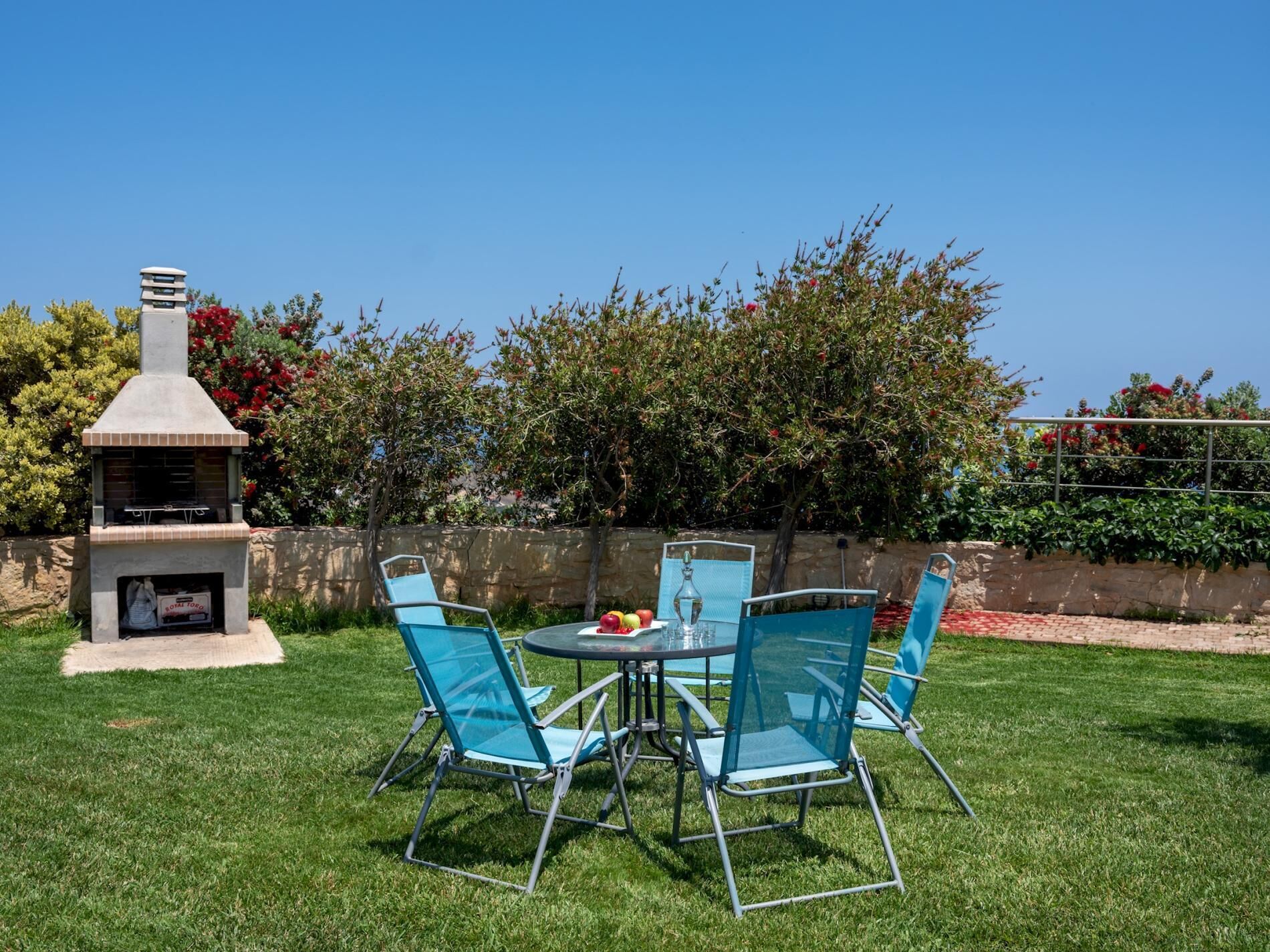 An outdoor patio with a barbecue grill, a round table, and four blue chairs.
