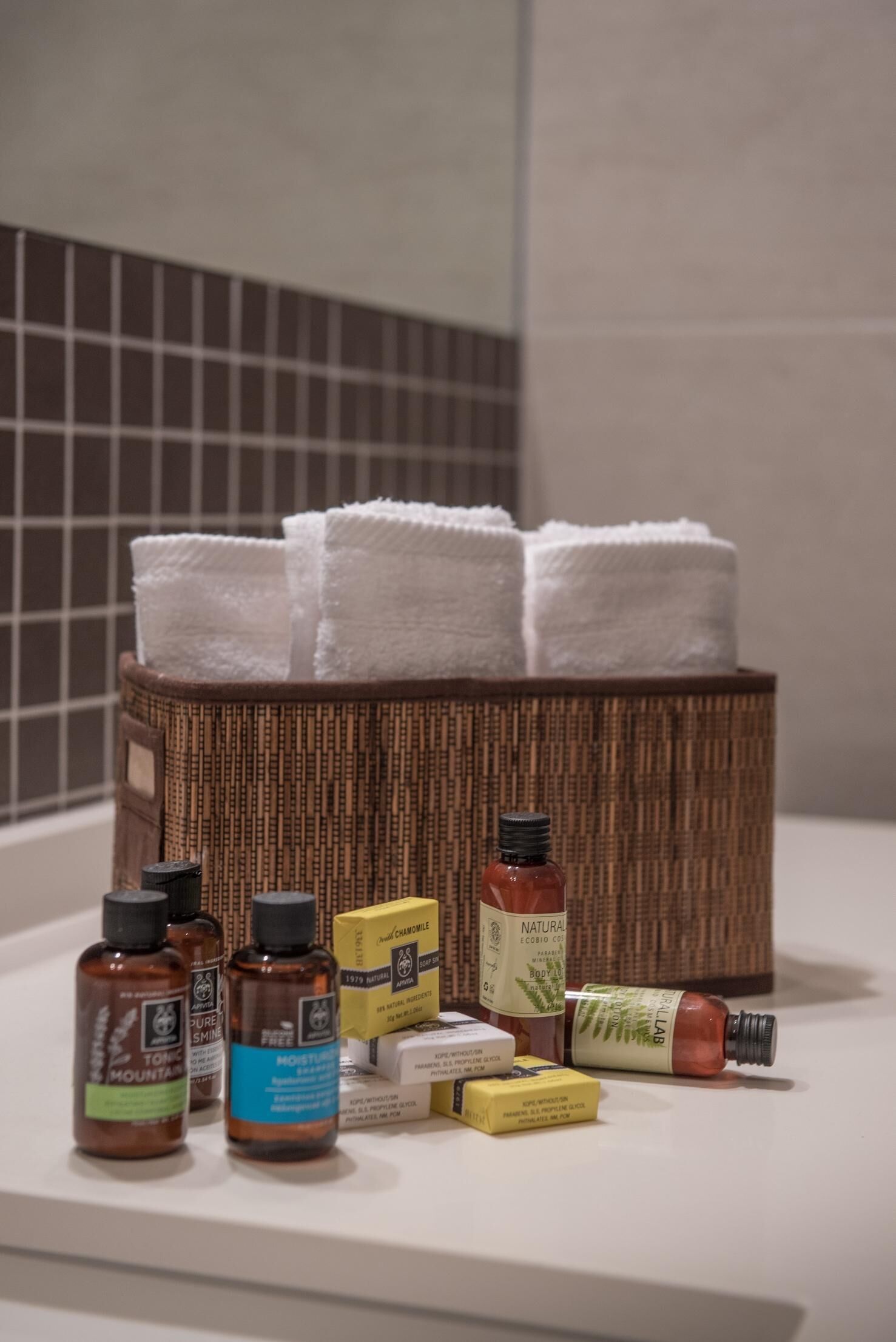 A bathroom with a wicker basket holding white towels, and various toiletries on the counter.
