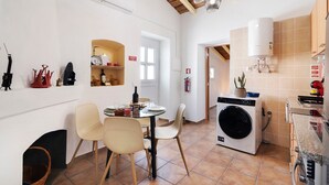 A compact kitchen with a washing machine, a dining area with chairs, and a small table.