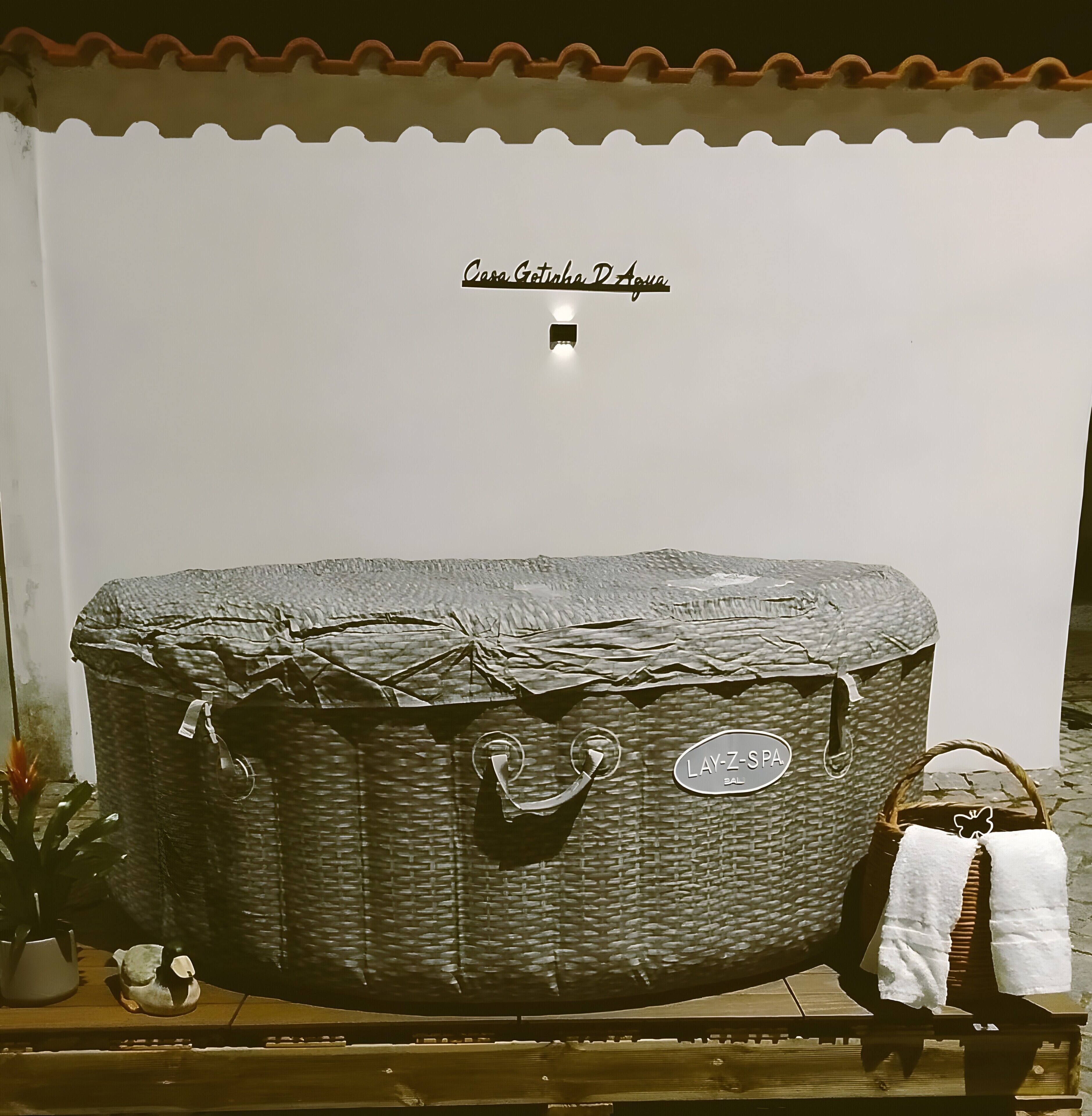 Eine Badewanne mit Lay-Z-Spa Aufschrift, einem Handtuch und einem kleinen Dekorationsobjekt auf einer Holzoberfläche.