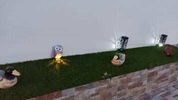 Un jardín con patos ornamentales, un comedero para pájaros y un aplique de pared.