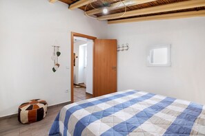 A bedroom with a bed, a wooden door, a wall-mounted hook, and a window.
