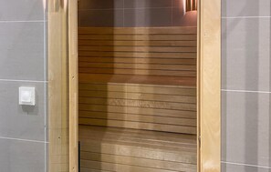 L’intérieur d’un ascenseur, avec des panneaux en bois disposés horizontalement et un interrupteur sur le mur.