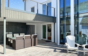 Eine moderne Außenpatio mit Korbmöbeln und einer Glastür zum Küchenbereich.