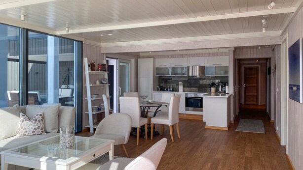 Un salon moderne avec une table basse en verre, un canapé blanc et un coin repas comprenant une petite table et des chaises.