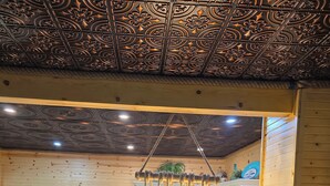 Een moderne keuken met een centraal eiland, roestvrijstalen apparatuur en een decoratief plafond.