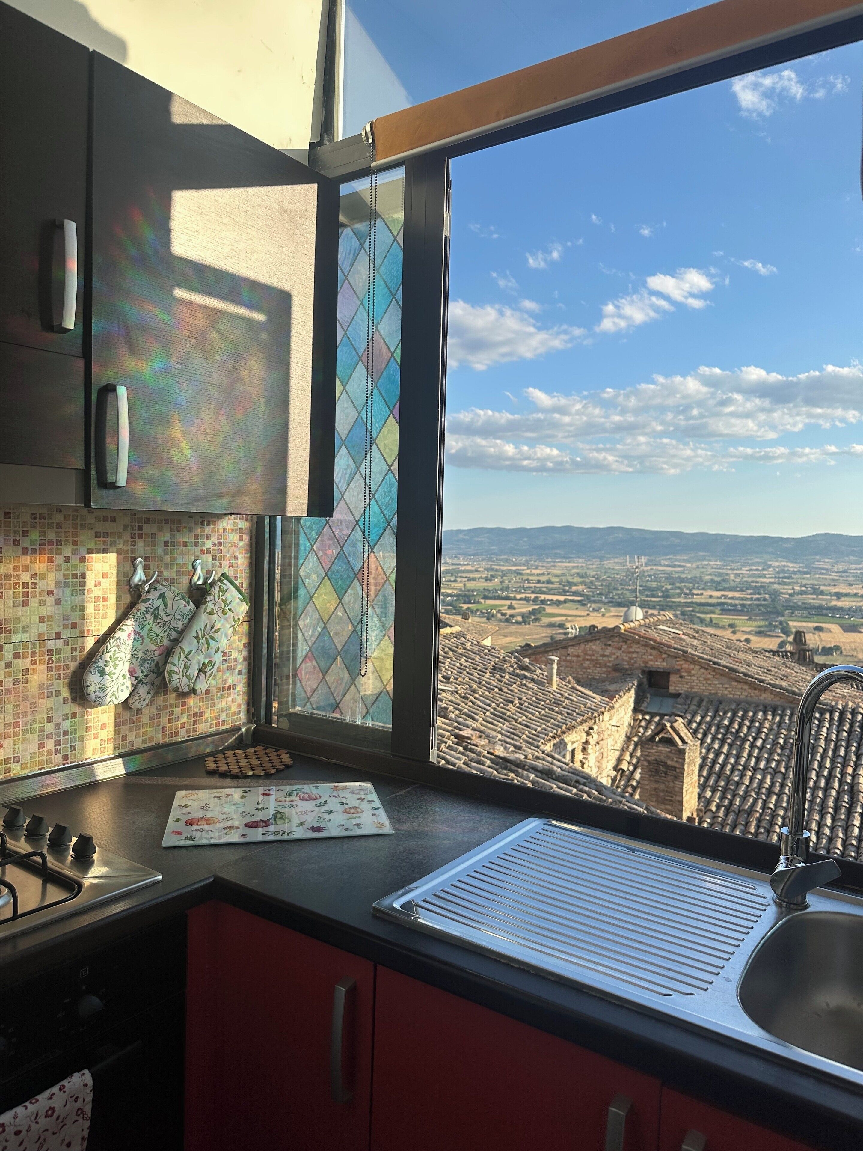 A kitchen with a large window, a stove, and a sink.
