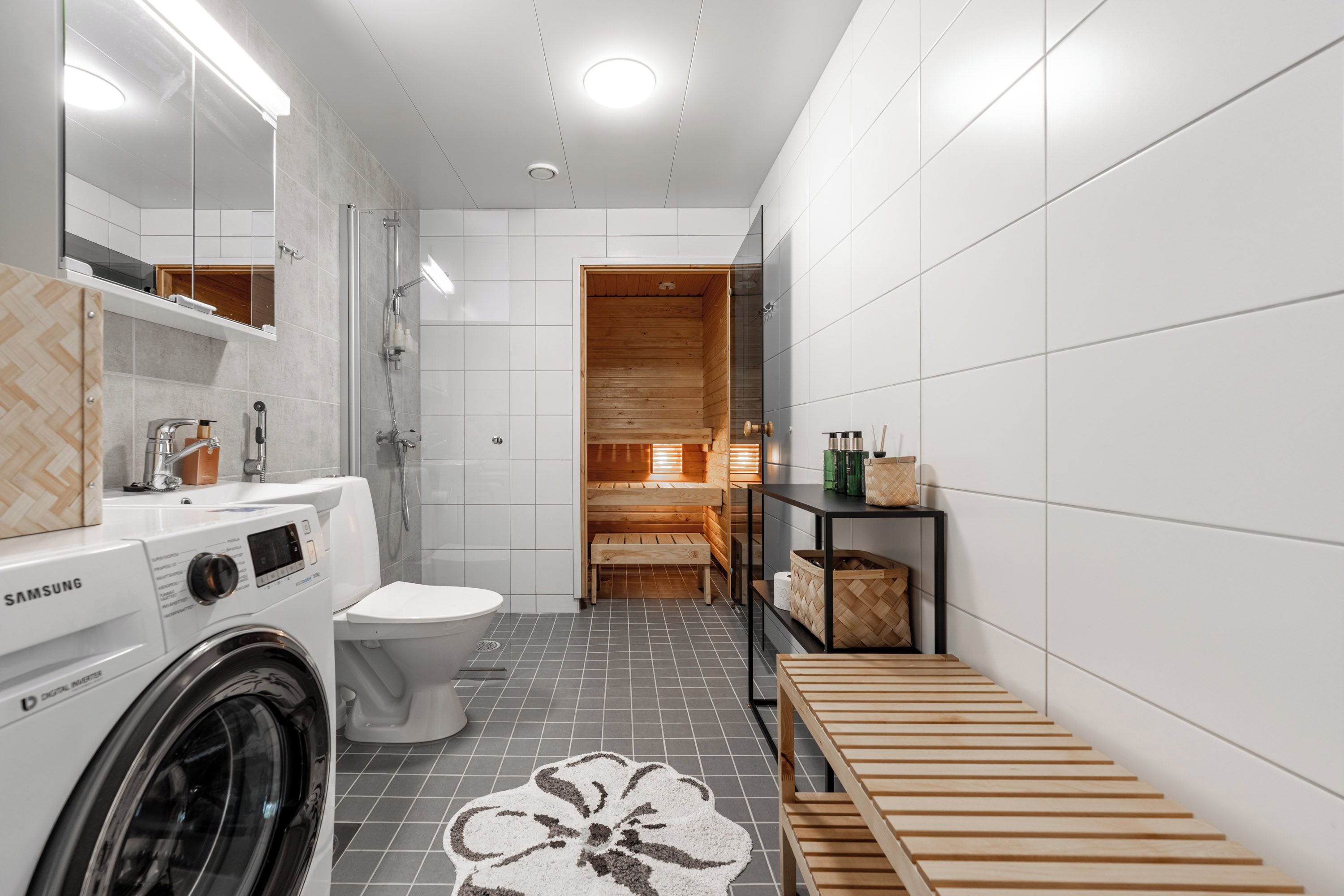 Un bagno moderno con lavatrice, WC e area sauna in legno.