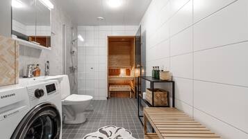 Un bagno moderno con lavatrice, WC e area sauna in legno.