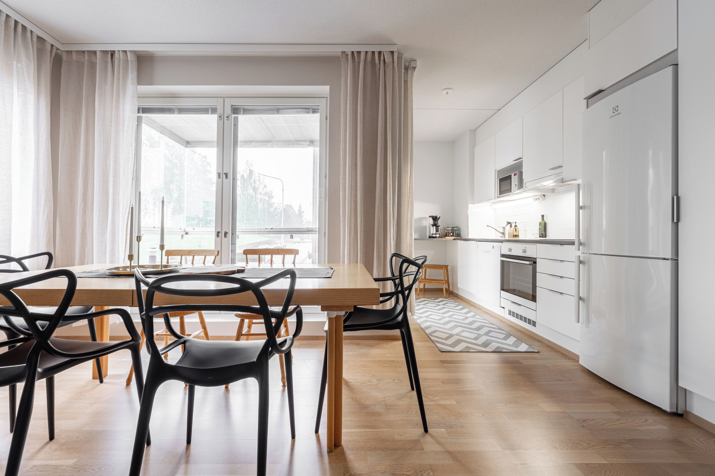 A modern kitchen with white cabinets, a built-in oven, and a microwave.